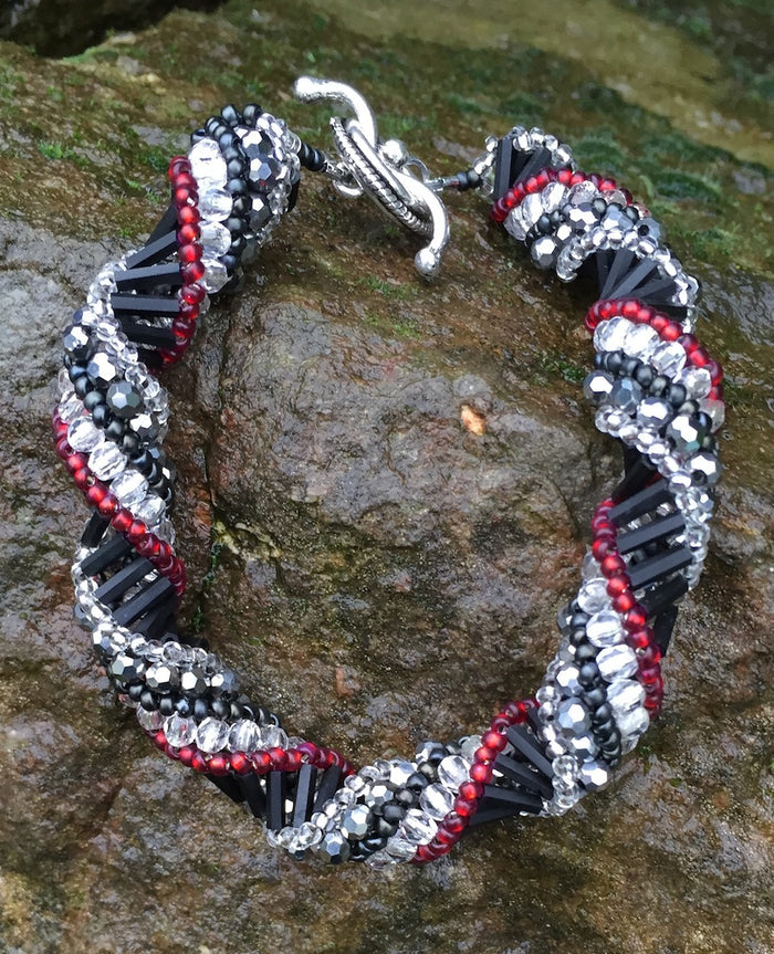This meticulously woven Helix Spiral Bracelet includes Czech fire-polished glass beads in Crystal, Red, Black and Metallic gray. 8 1/4" and 8 1/2"