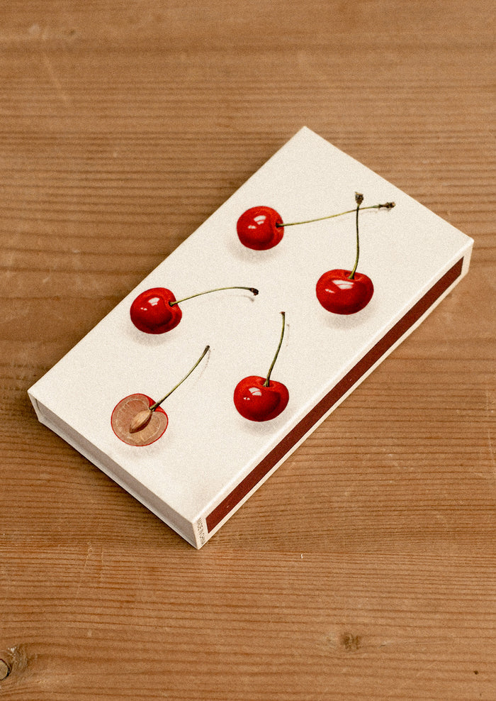 Matchbox with cherries on a wooden surface