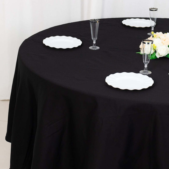 Elegant black tablecloth with white plates and decorative flowers.