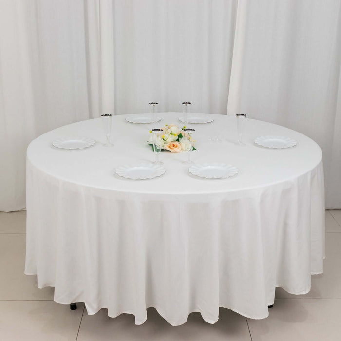 Round table set with white tablecloth and plates, decorated with flowers.
