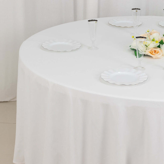 Round table set with white plates and floral centerpiece.