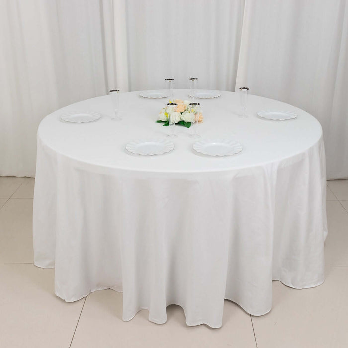 Round dining table set with white tablecloth and decorative flowers.