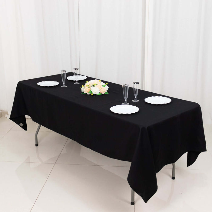 Elegant black table setup with white plates and floral centerpiece.
