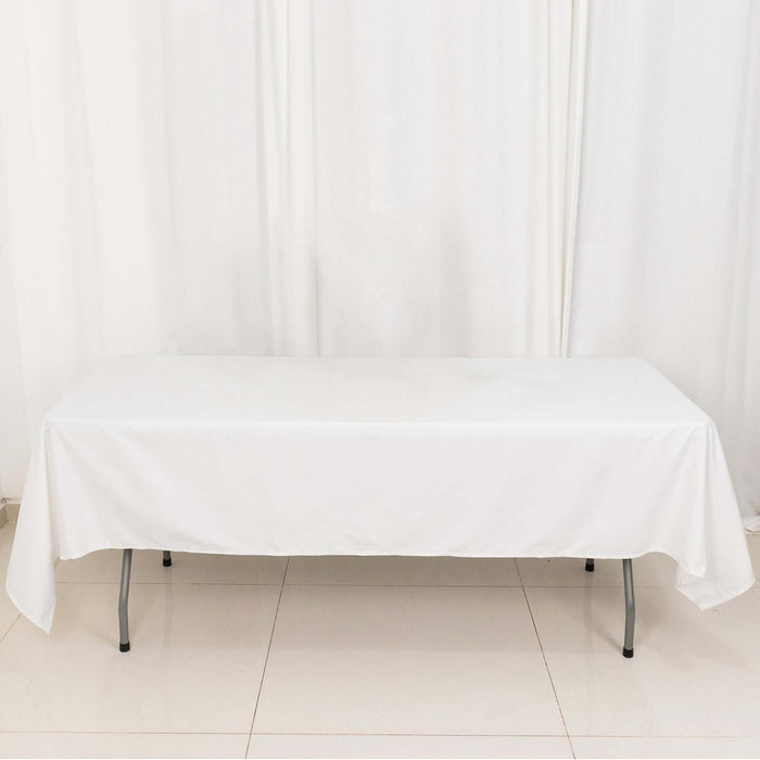 White table with a fitted tablecloth on a plain background