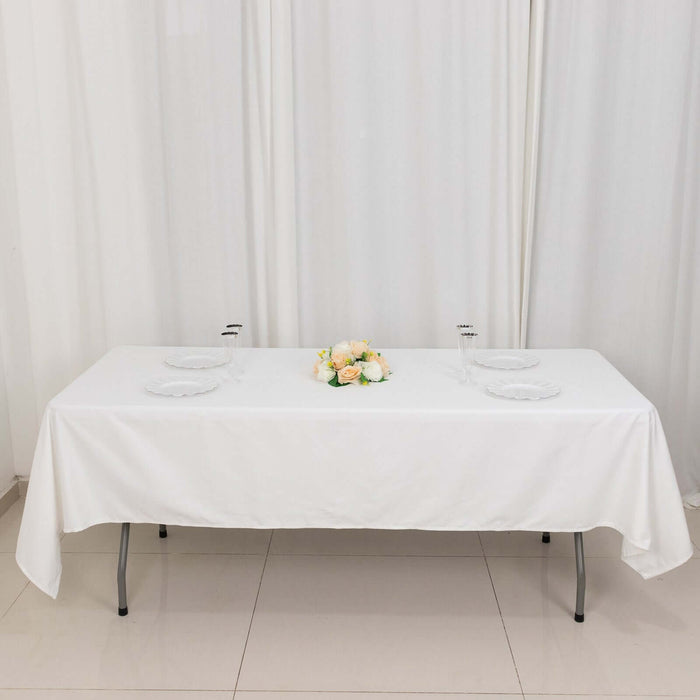 White table set for dining with plates and a flower centerpiece.