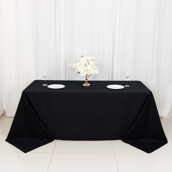 Elegant black tablecloth with floral centerpiece and table settings.