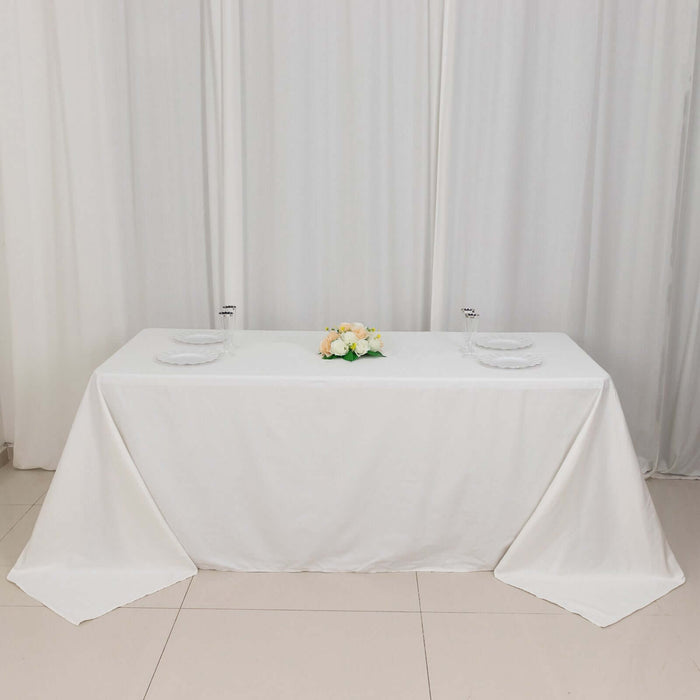 Elegant white table set for dining with floral centerpiece.