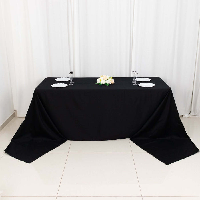 Black tablecloth draped over a table with plates and floral centerpiece