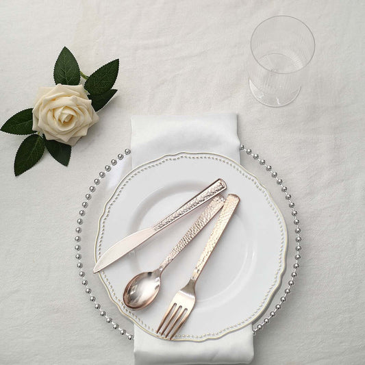 Elegant table setting with silver cutlery, white plate, and rose on a napkin.
