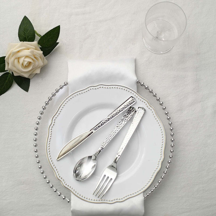 Elegant silver cutlery set on a decorative plate with a white rose