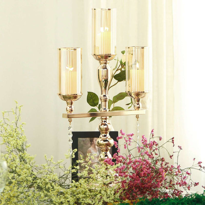 Elegant gold candle holder with three glass shades and floral decoration.