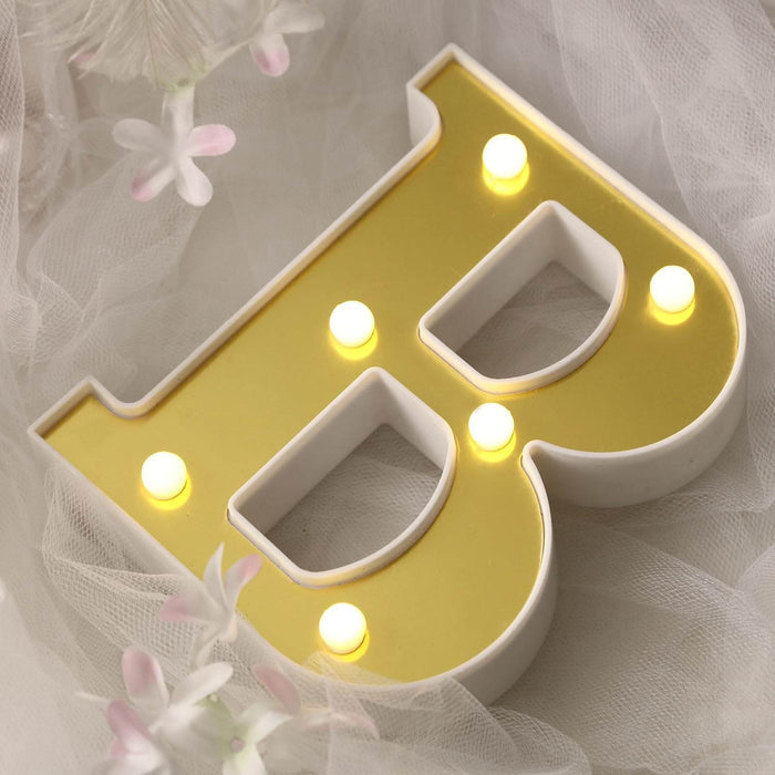 Decorative illuminated letter "B" with yellow lights on a white backdrop
