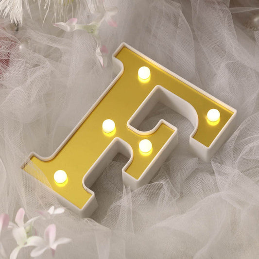 Gold letter F light up sign on soft fabric backdrop.