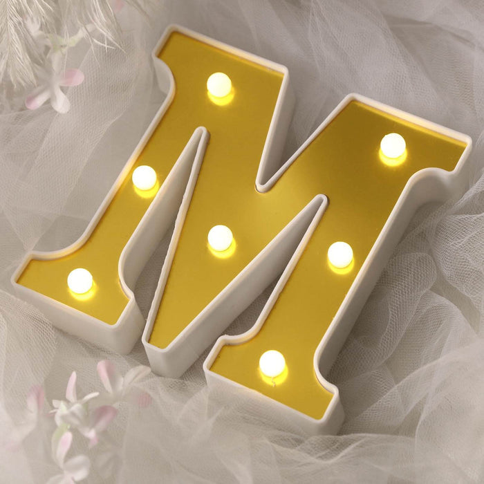 Yellow light-up letter "M" on a soft white background.