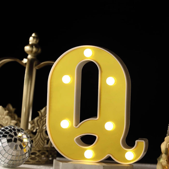 Yellow marquee letter "q" with lights, decorative display piece. #whtbkgd