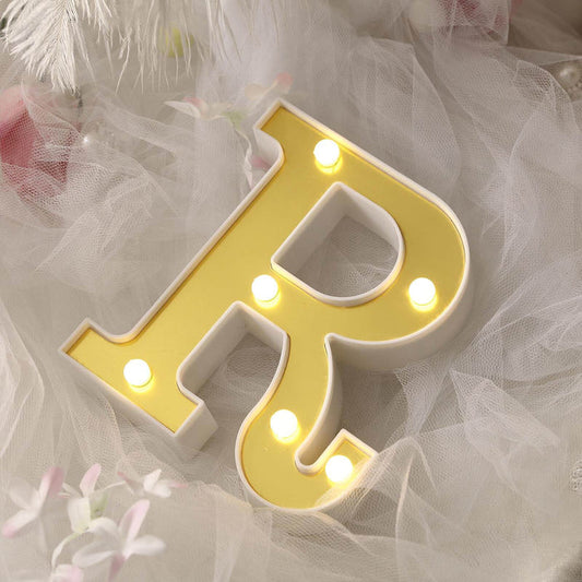 Yellow marquee letter "R" with lights on soft white fabric backdrop.