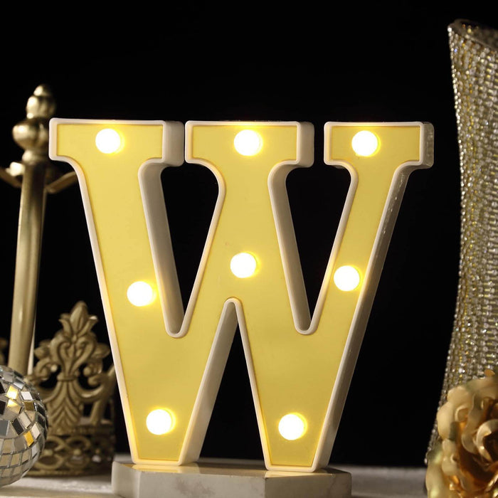 Yellow marquee letter "W" illuminated with light bulbs on a decorative display. #whtbkgd