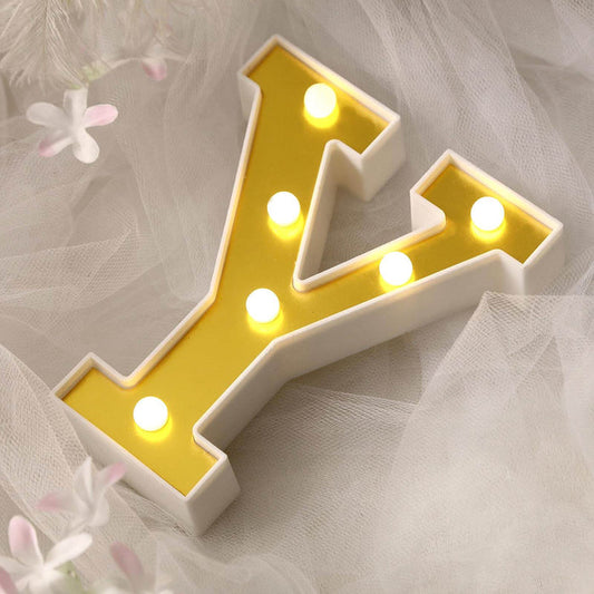 Yellow marquee letter "Y" with lights on a soft, textured background.