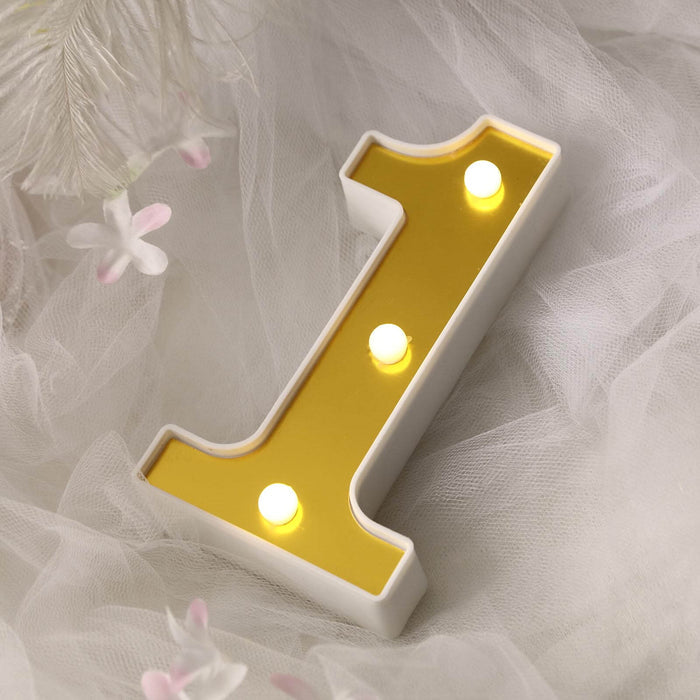 Gold and white number one light decoration on soft fabric backdrop.