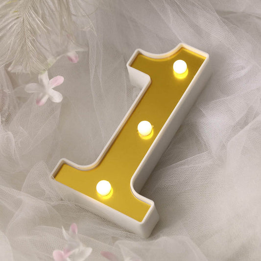 Gold and white number one light decoration on soft fabric backdrop.