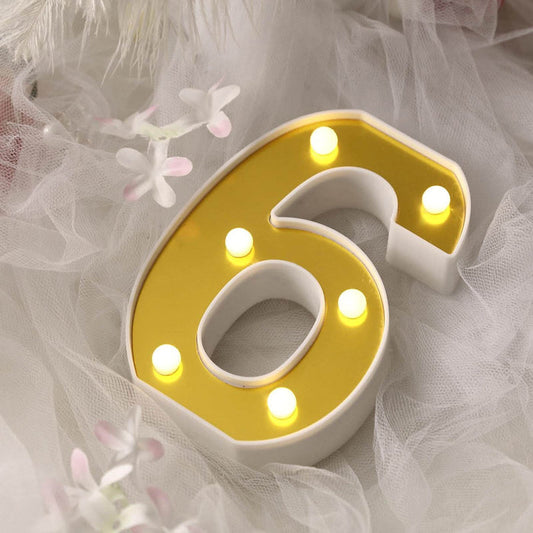 Gold and white illuminated number 6 decorative light.