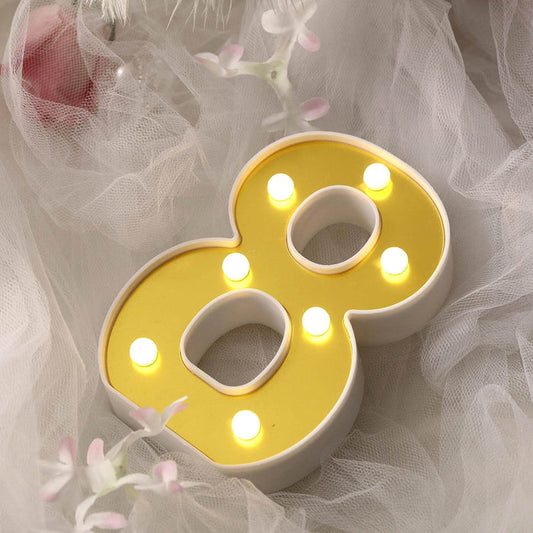 Yellow LED number 8 light decor on a soft white fabric background.