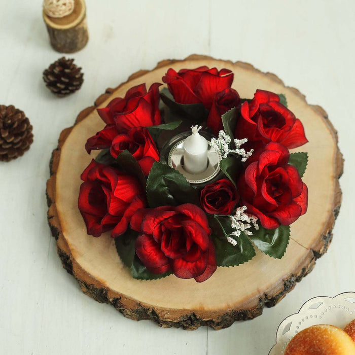 Red artificial roses centerpiece with a candle on a wooden slice.
