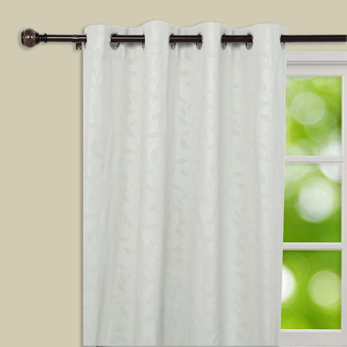 Sheer white curtain panel with leaf pattern, hanging on a rod.