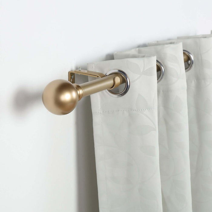 Gold curtain rod with decorative finial and light gray patterned curtains