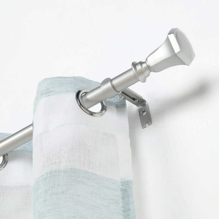 Silver curtain rod with decorative finial and sheer striped curtain