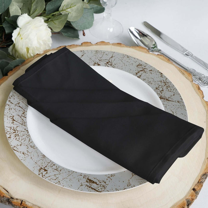 Black table napkin elegantly folded on a decorative plate.