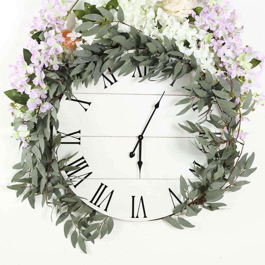 Floral wall clock with greenery and purple flowers on a white backdrop