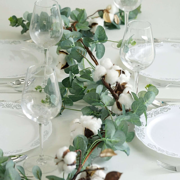 Elegant table setting with glasses and cotton greenery centerpiece.