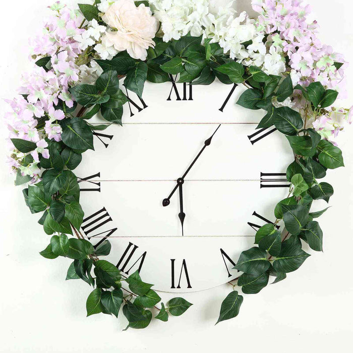Floral wall clock with Roman numerals and greenery decoration.