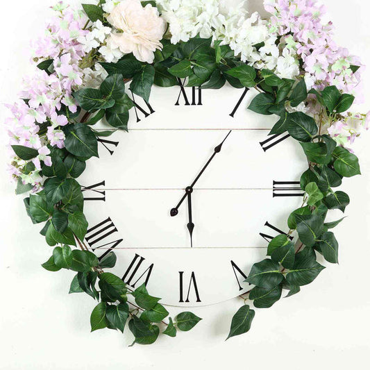 Floral wall clock with Roman numerals and greenery decoration.