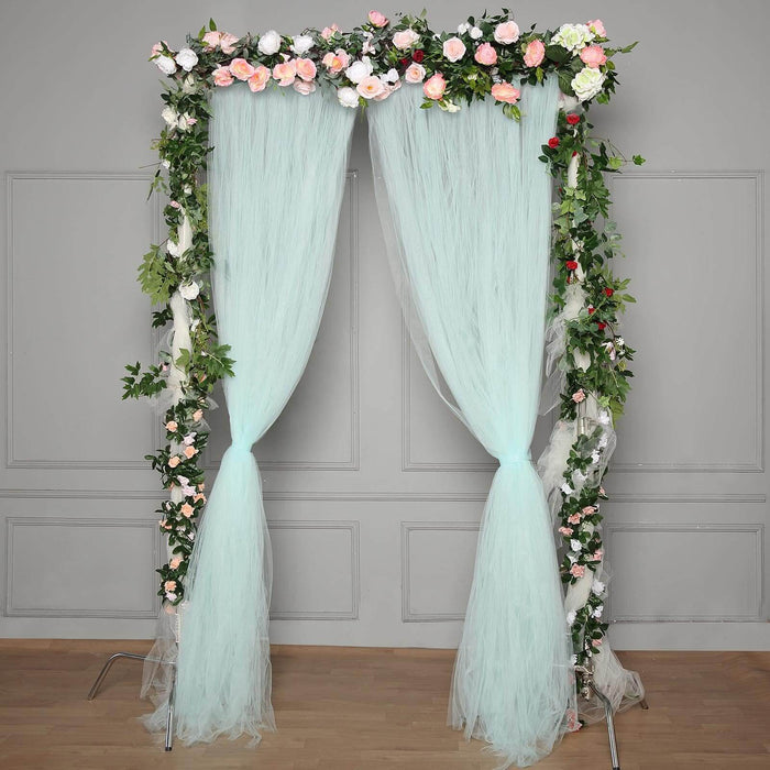 Floral wedding arch with pastel tulle and greenery decorations.
