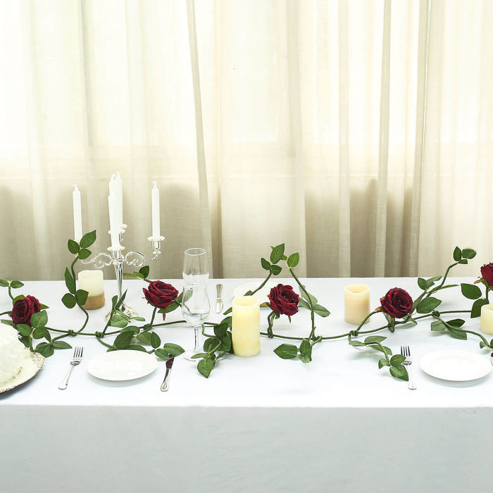 Elegant table setting with red roses, candles, and silver cutlery.