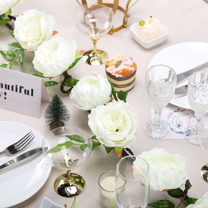 Elegant table setting with faux flowers, glassware, and decorative items.