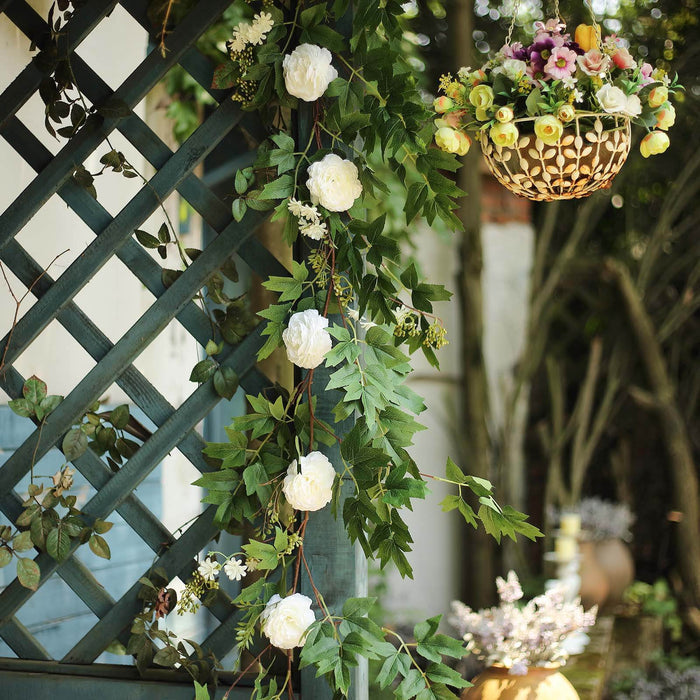 Decorative floral garland with white roses and greenery on a trellis.