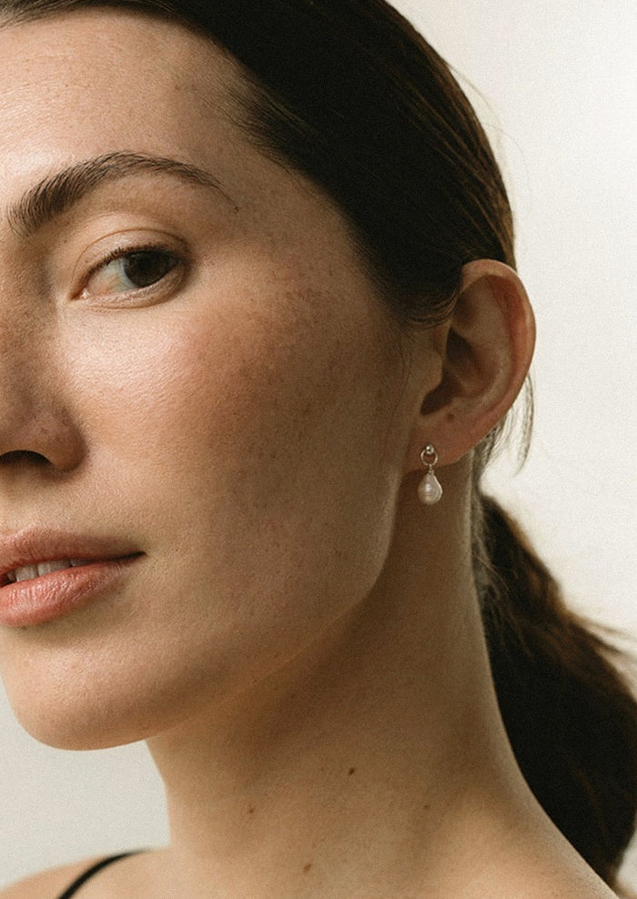 A pair of dangling pearl earrings.