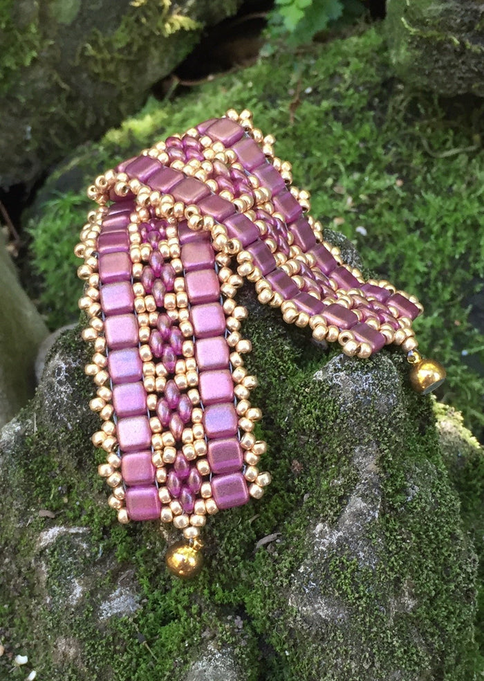 This bead woven bracelet combines gold toned Pink Czech Glass tiles with Pink and Gold glass beads and measures 6 3/4".
