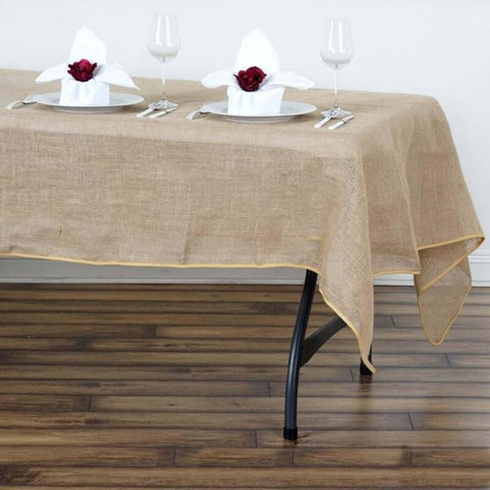 Burlap tablecloth with yellow trim on a dining table set for two.