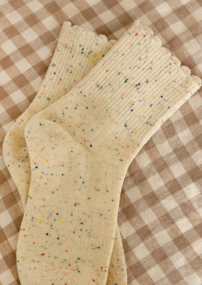 A pair of cream socks with multicolor speckles.