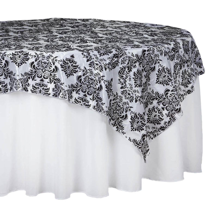 Black and white damask tablecloth draped over a round table.