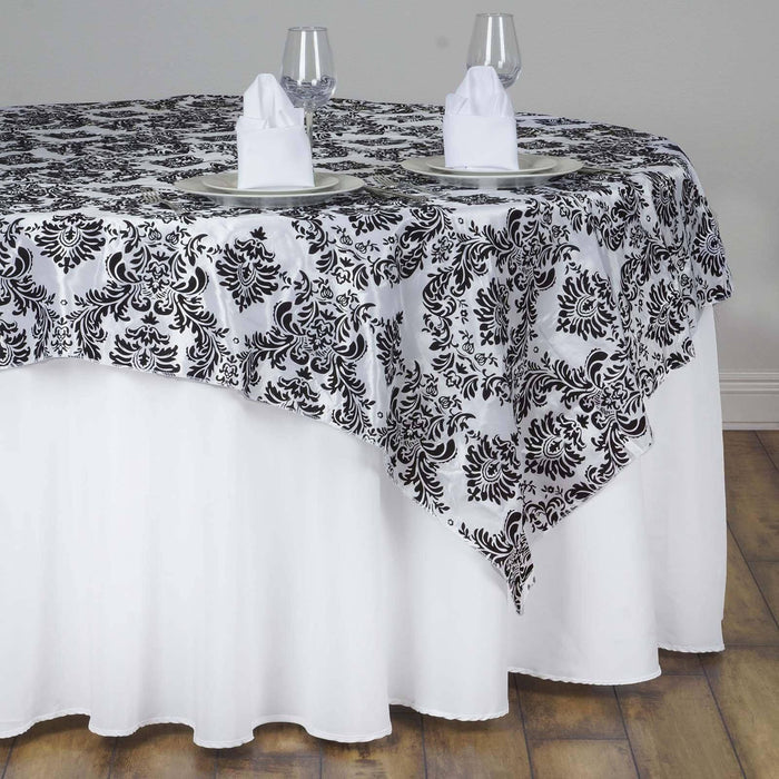 Elegant black and white damask tablecloth on a round table with dinnerware.