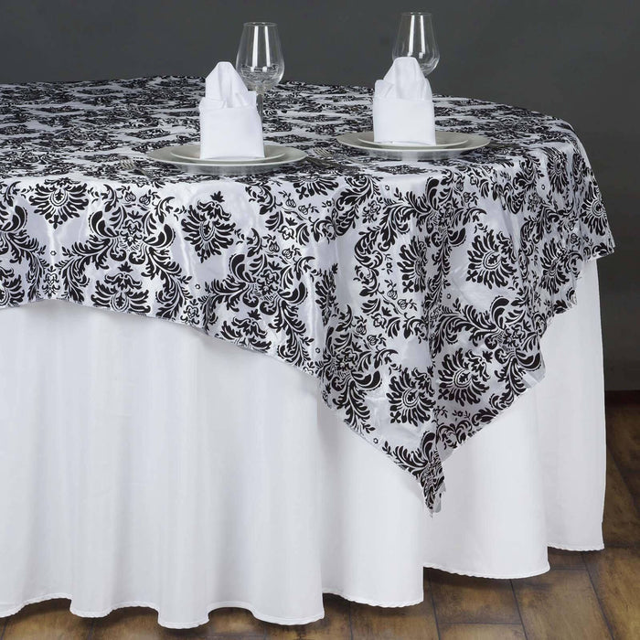 Black and white damask tablecloth draped over a round table setting.
