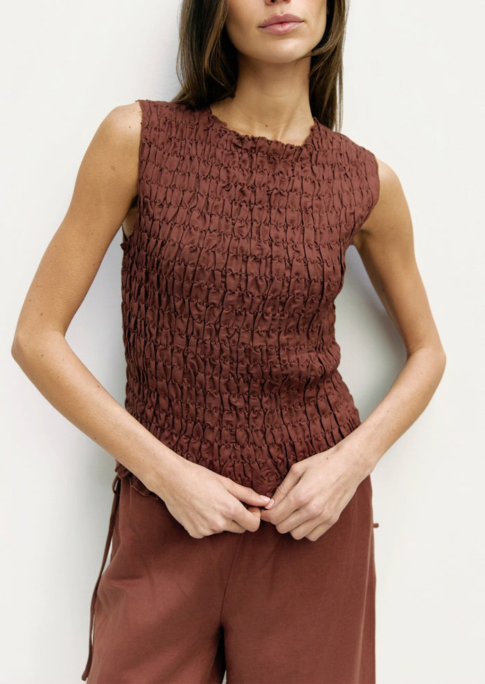 Woman wearing a brown textured top and pants against a white background