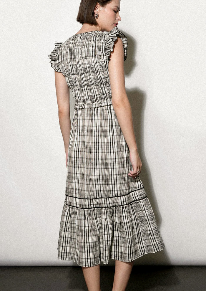 Woman wearing a black and white plaid dress against a white background.