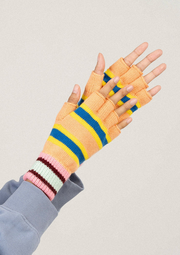 Colorful striped gloves worn on a neutral background