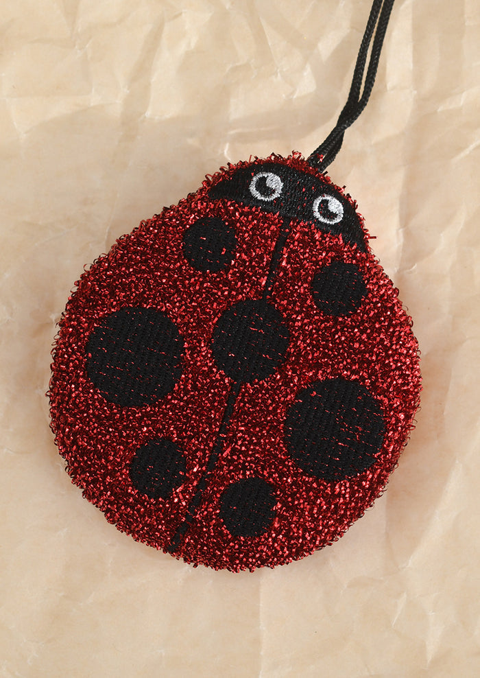 Red and black ladybug kitchen sponge on a beige background
